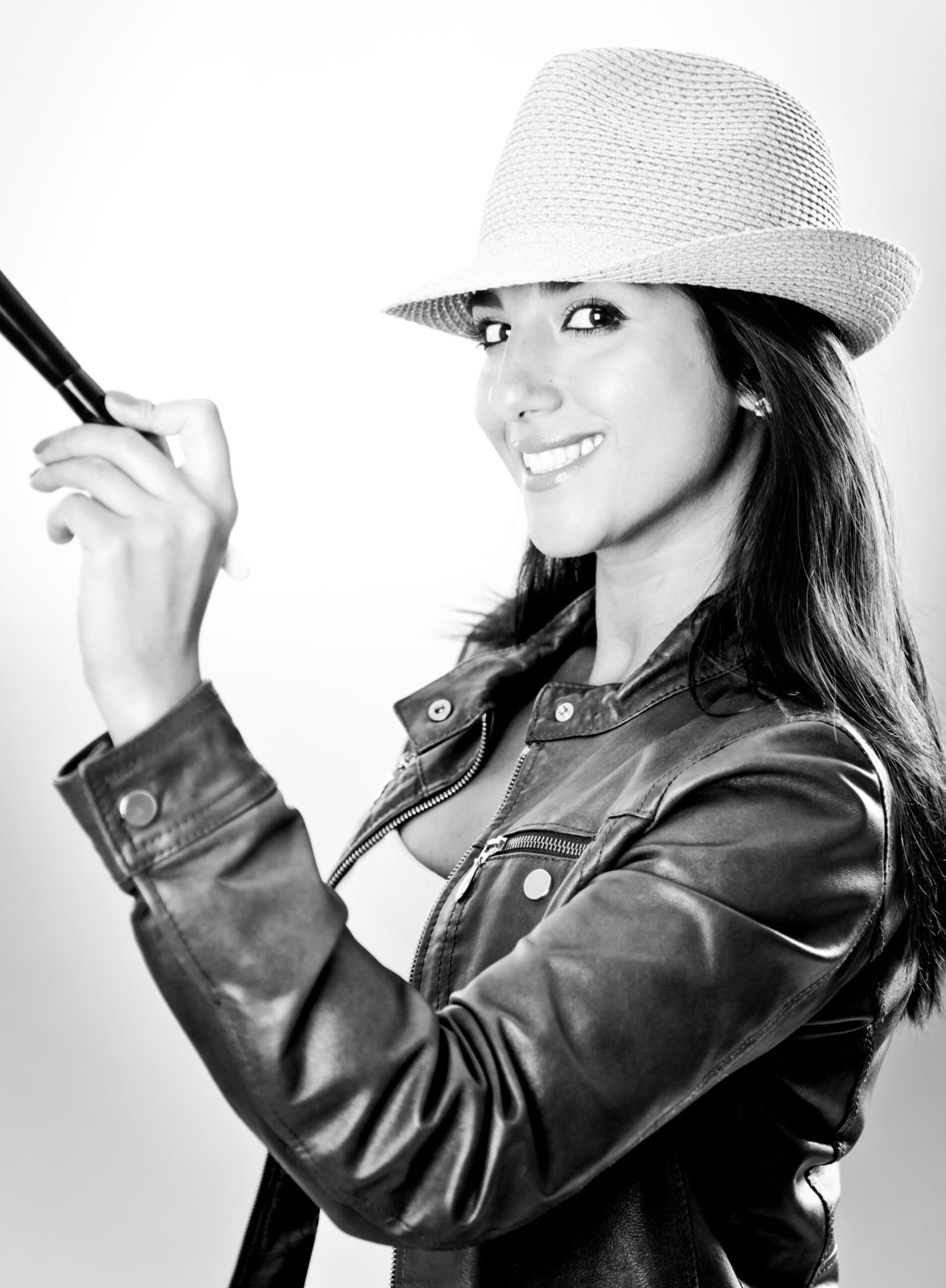 Neda, Schwarzweiss-Studioporträt mit Strohhut, Lederjacke und Pinsel in der Hand