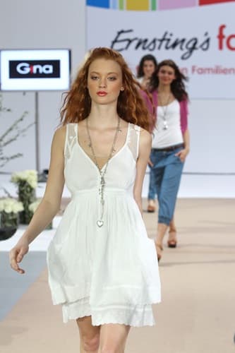 Model im weissen Kleid mit roten Locken auf dem Laufsteg